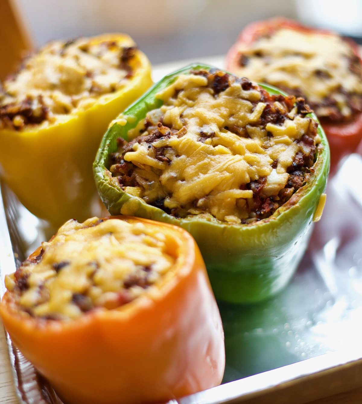 Green, yellow, orange and red bell peppers stuffed with ground meat and melted cheese