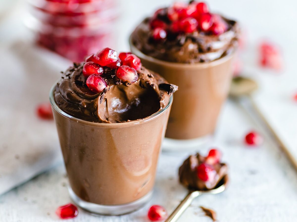 Two glasses of avocado chocolate mousse topped with pomegranate seeds