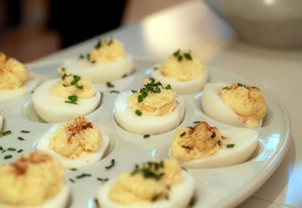 Deviled eggs with chives and paprika on a white egg platter