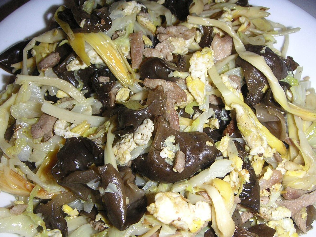 Stir-fried shredded cabbage with sliced pork, scrambled egg and wood ear mushrooms on a white plate