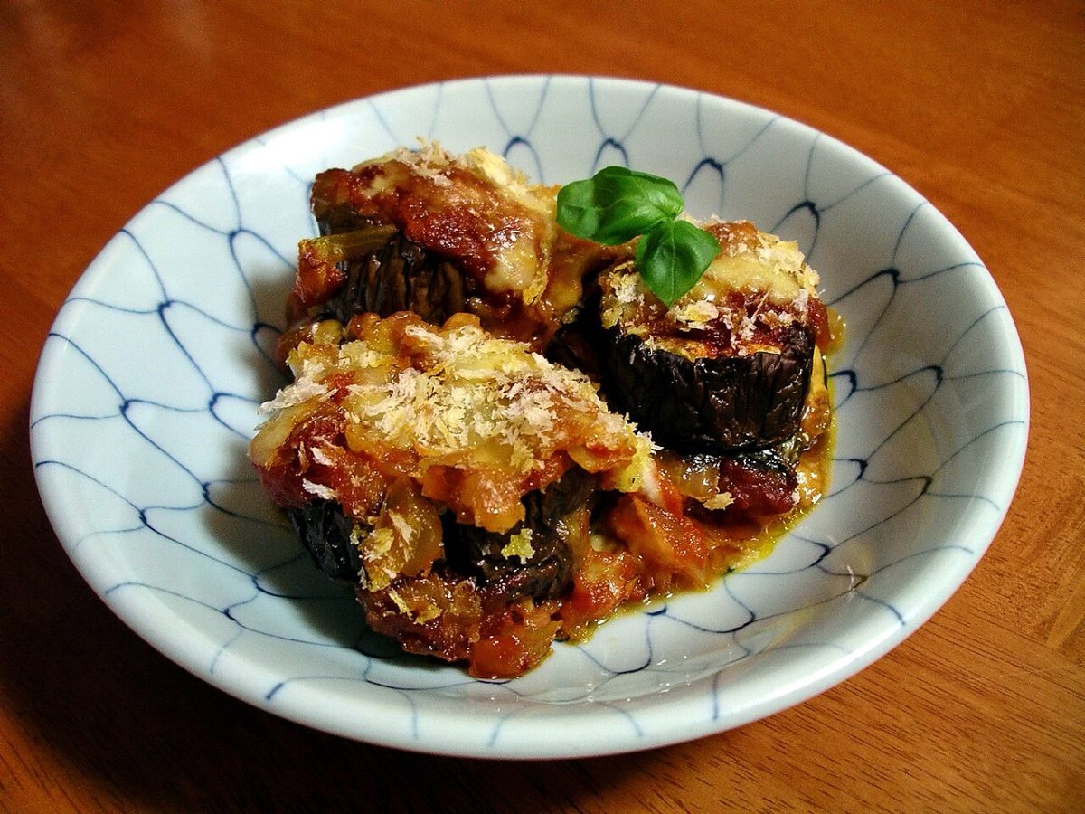 Baked eggplant rounds with tomato sauce, melted cheese and basil in a bowl