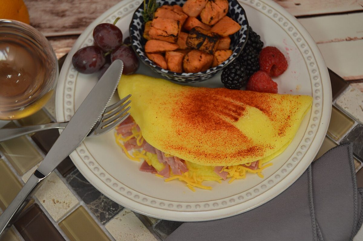A folded omelet filled with ham and melted cheese on a white plate