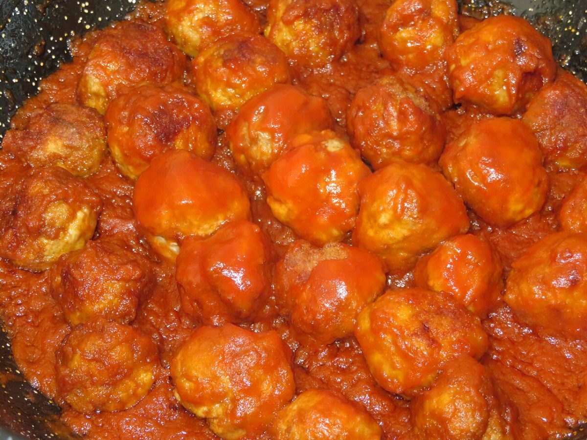 A pan full of meatballs simmering in thick tomato sauce