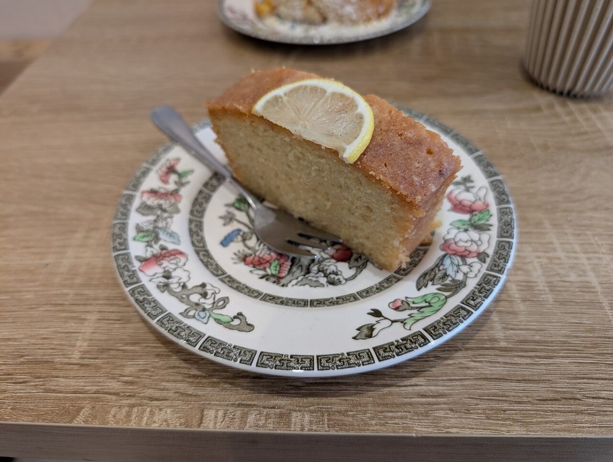 A slice of lemon cake topped with a lemon slice on a floral plate