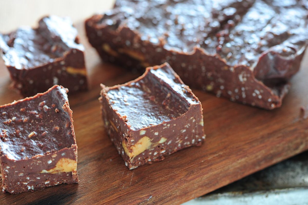 Squares of chocolate fudge with peanut butter swirls on a wooden board
