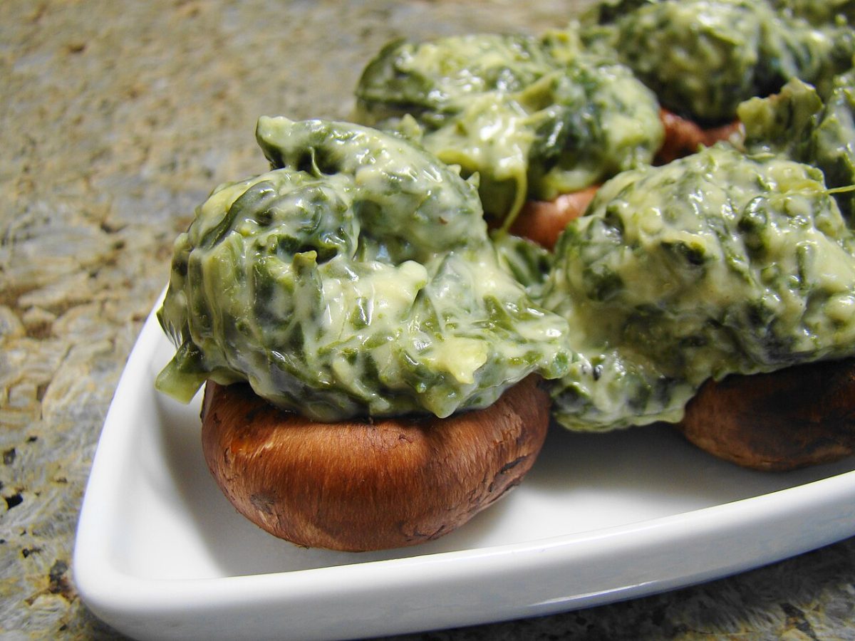 Brown mushroom caps topped with creamy spinach filling on a white dish