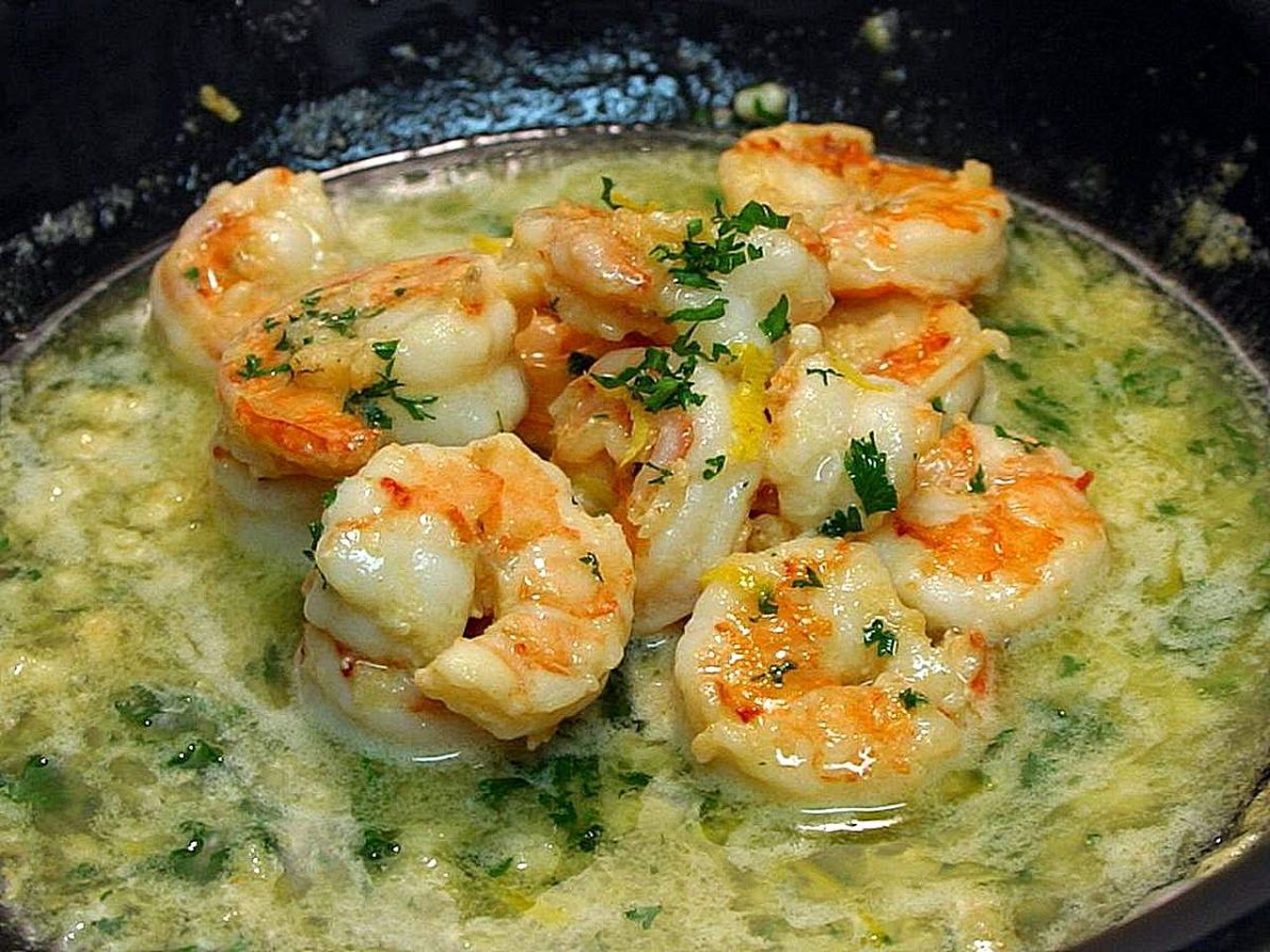 Shrimp scampi in garlic butter sauce with chopped parsley and lemon zest